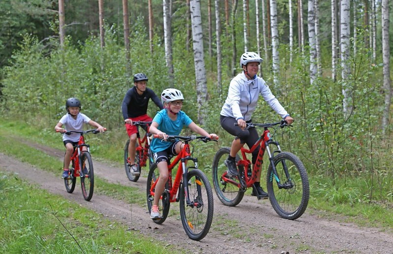 Familj som cyklar längs en grusväg.