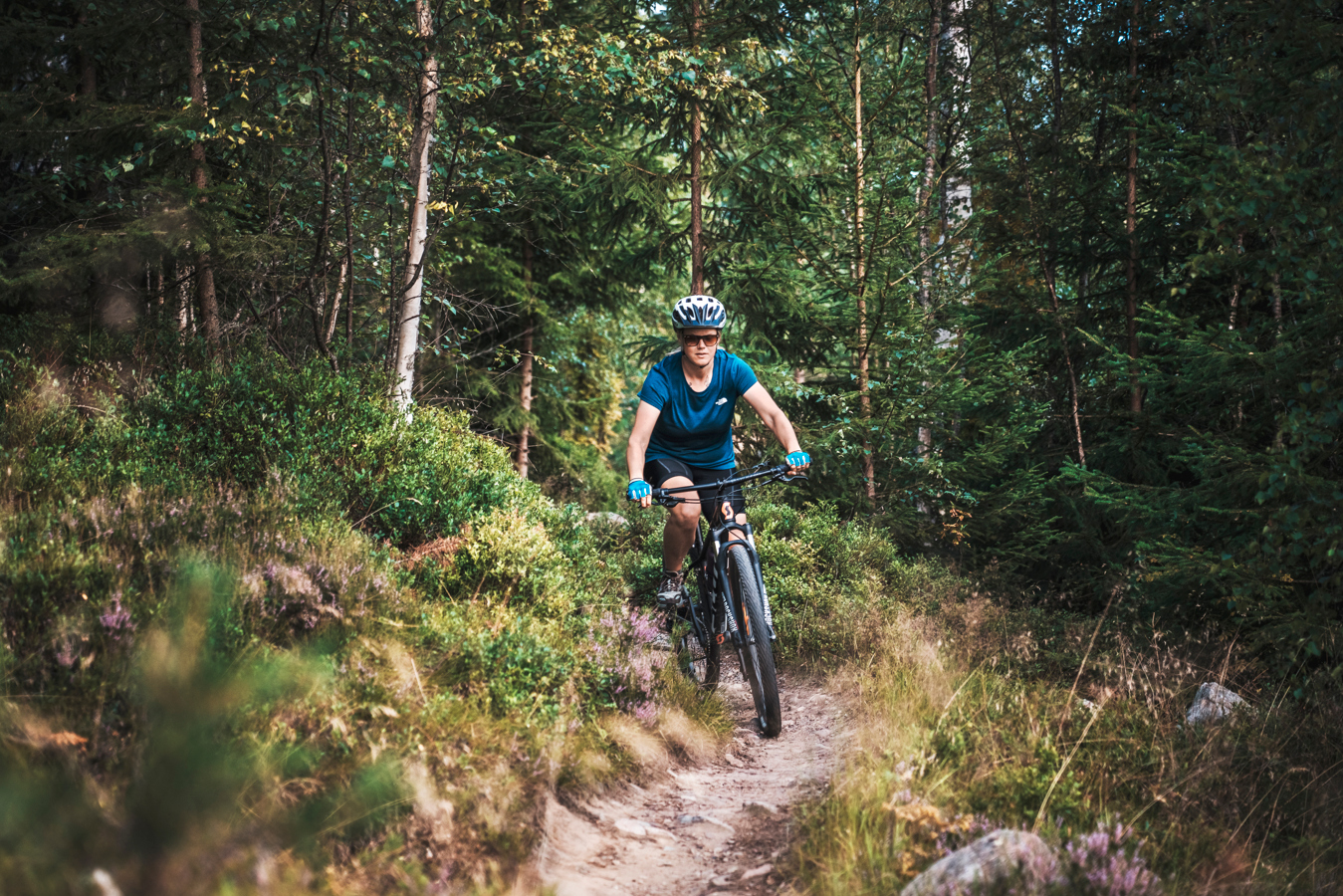 En kvinna cyklar mountainbike i skogen.