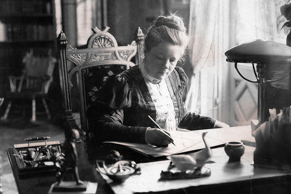 Selma Lagerlöf sitter vid sitt skrivbord och skriver.