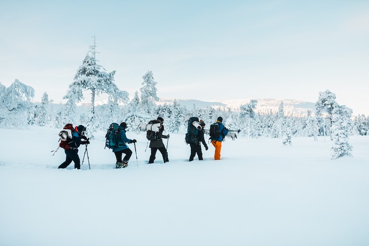 Personer som vandrar i snön med ryggsäck.