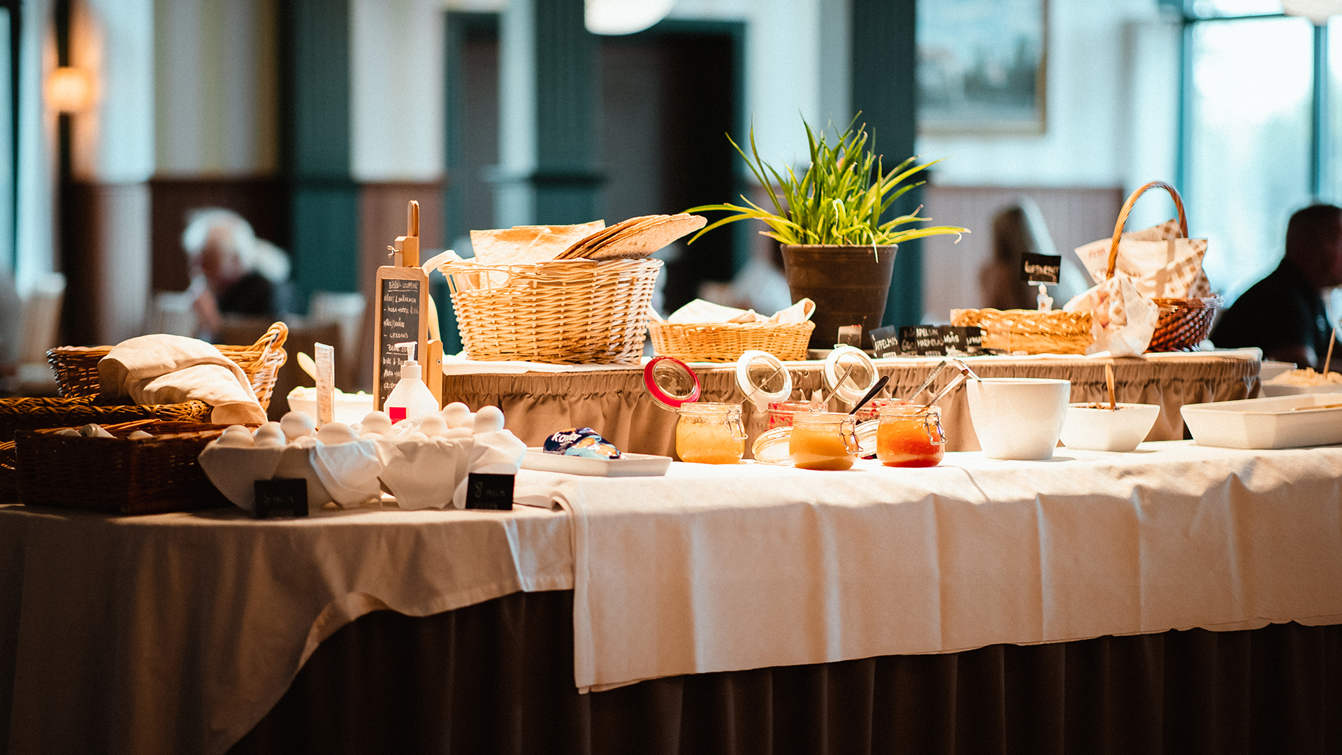En frukostbuffé står uppdukad på ett bord med vit duk.