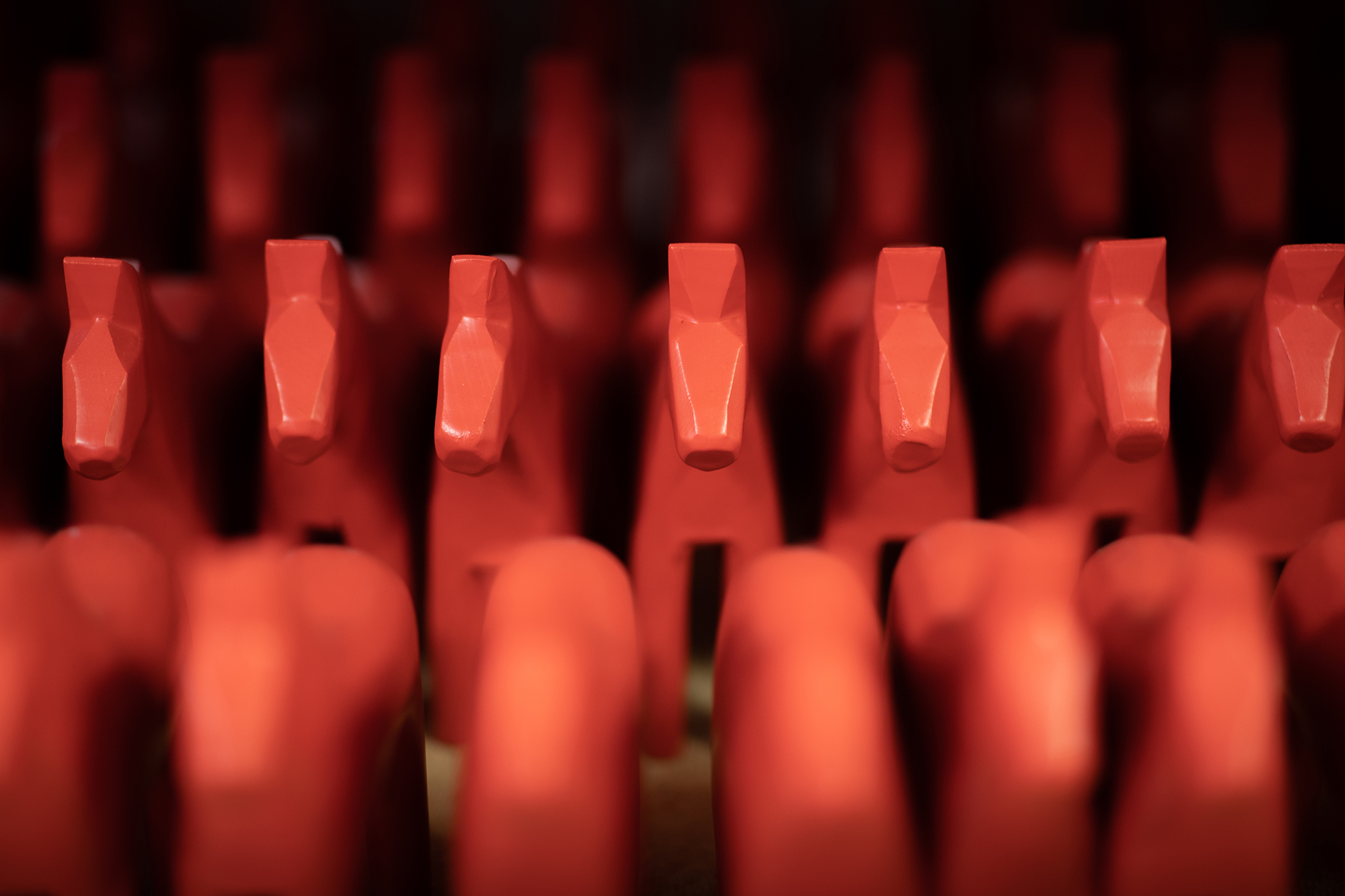 Nymålade röda dalahästar på rad.