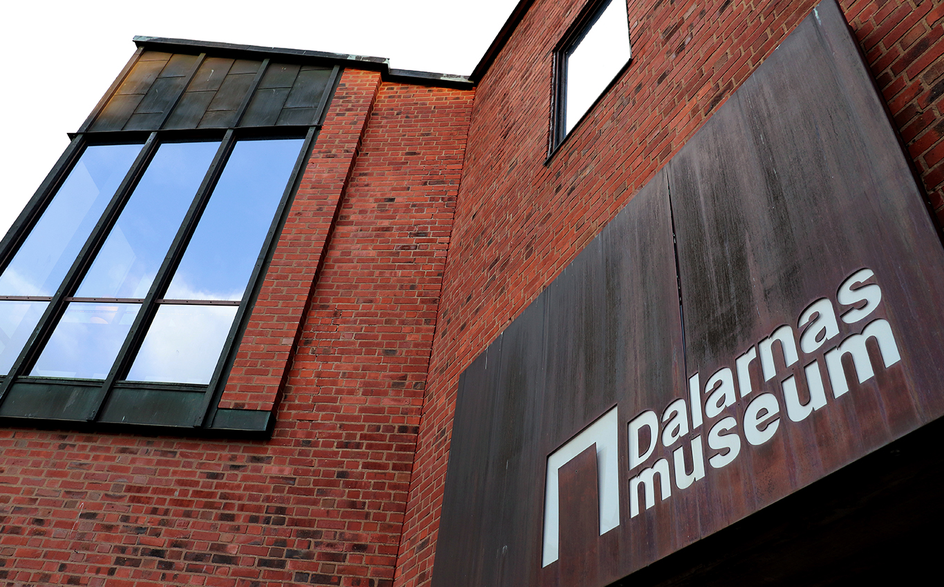 En tegelfasad med röda fönster och texten Dalarnas musuem.