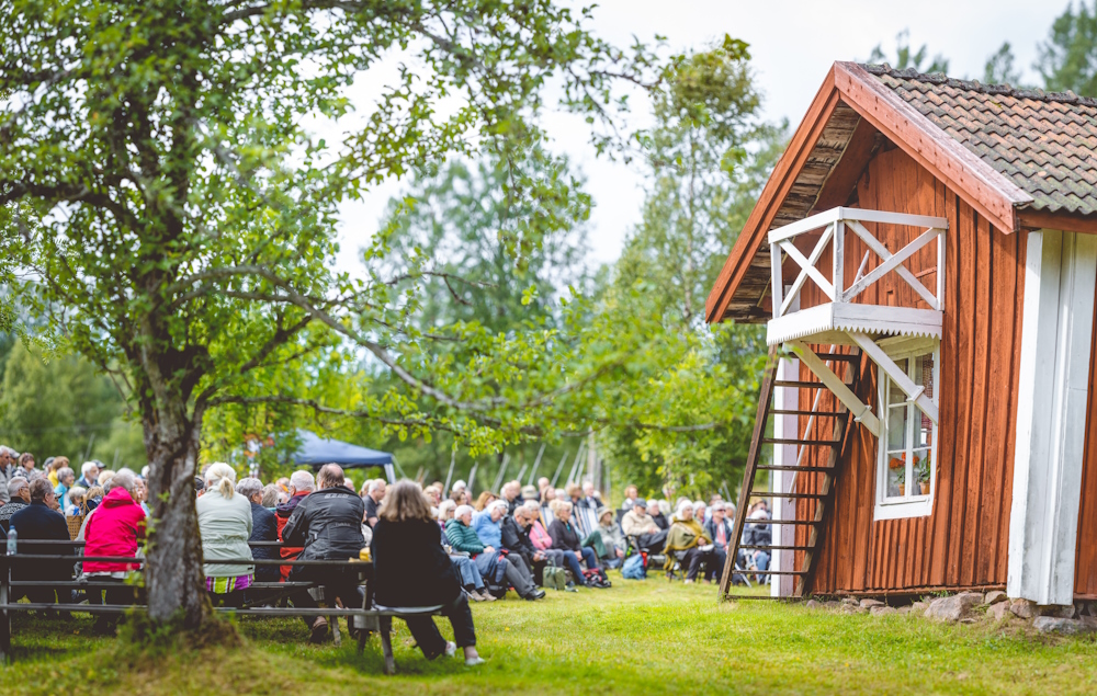 Luossastugan med publik sittandes i trädgården.