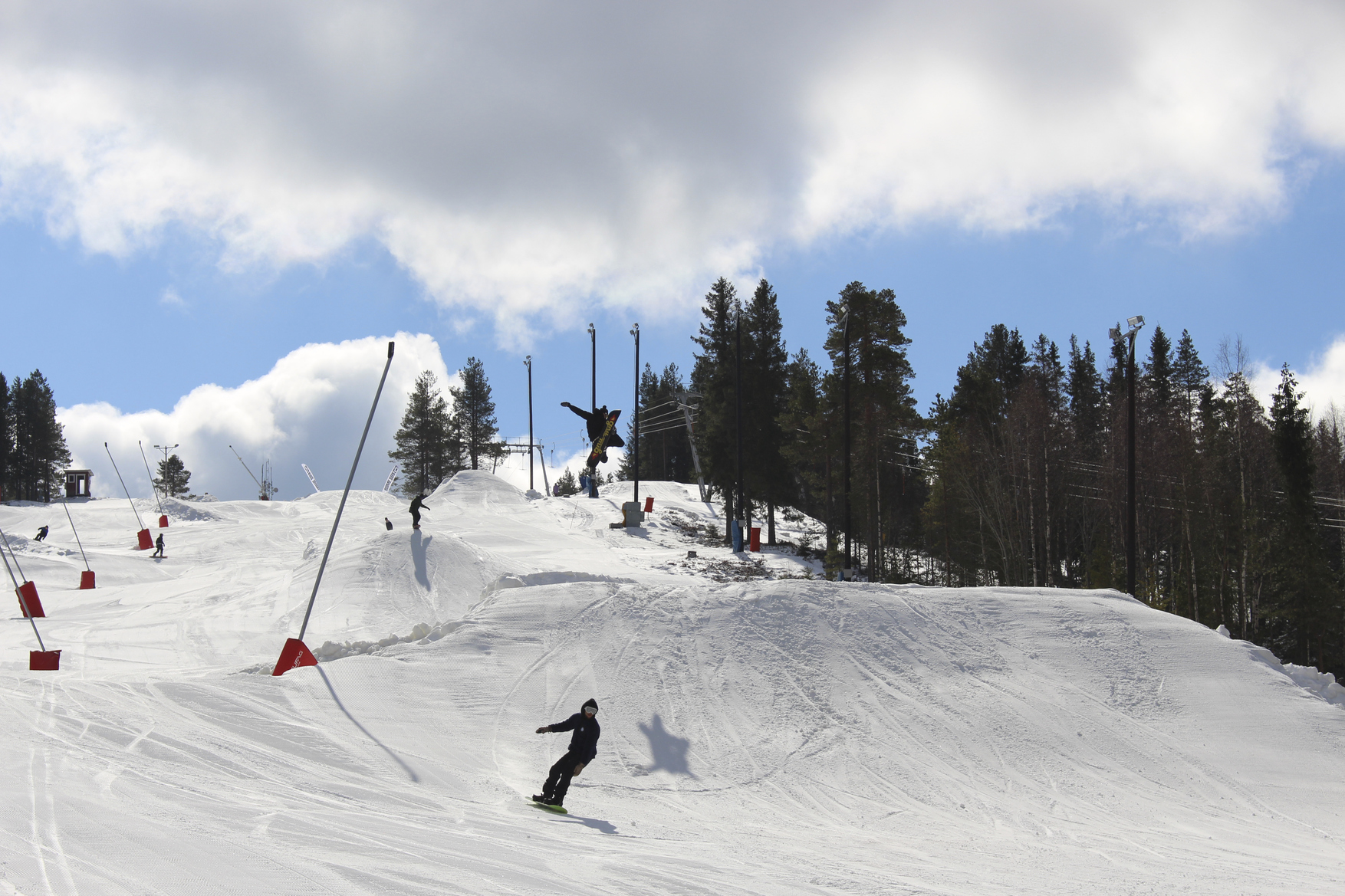 En snowboardåkare susar ned för solig backe.