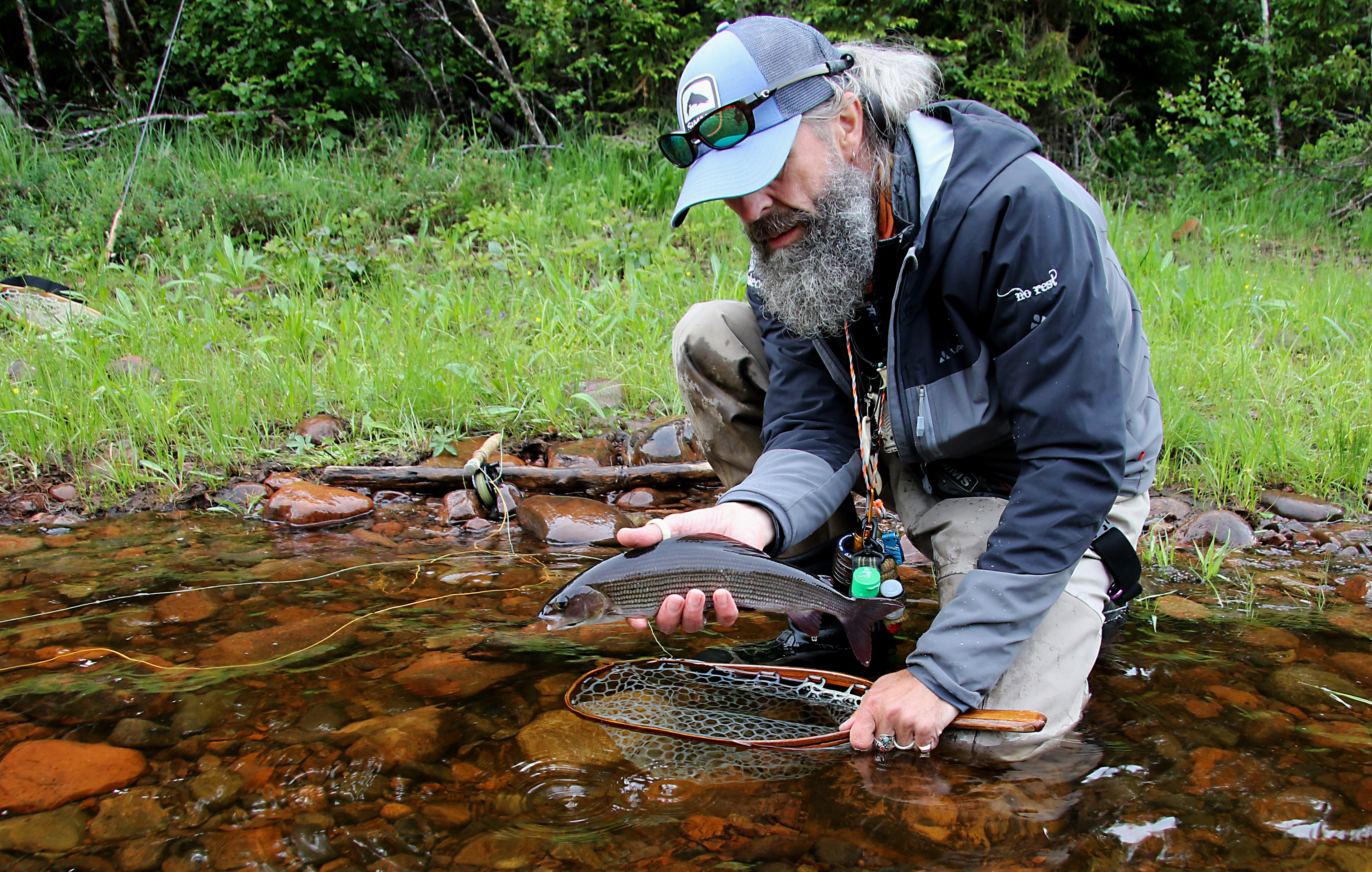Fiskare som håller i en fisk intill en älv.
