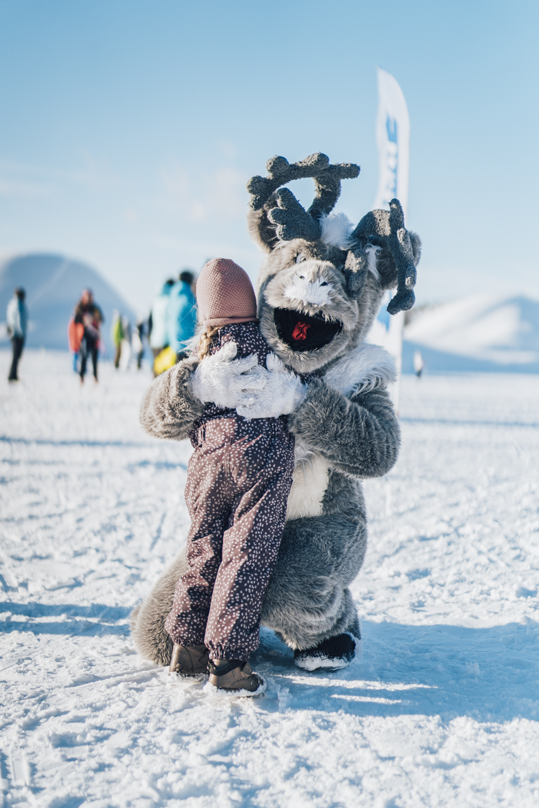 Maskot Aske kramar ett barn.