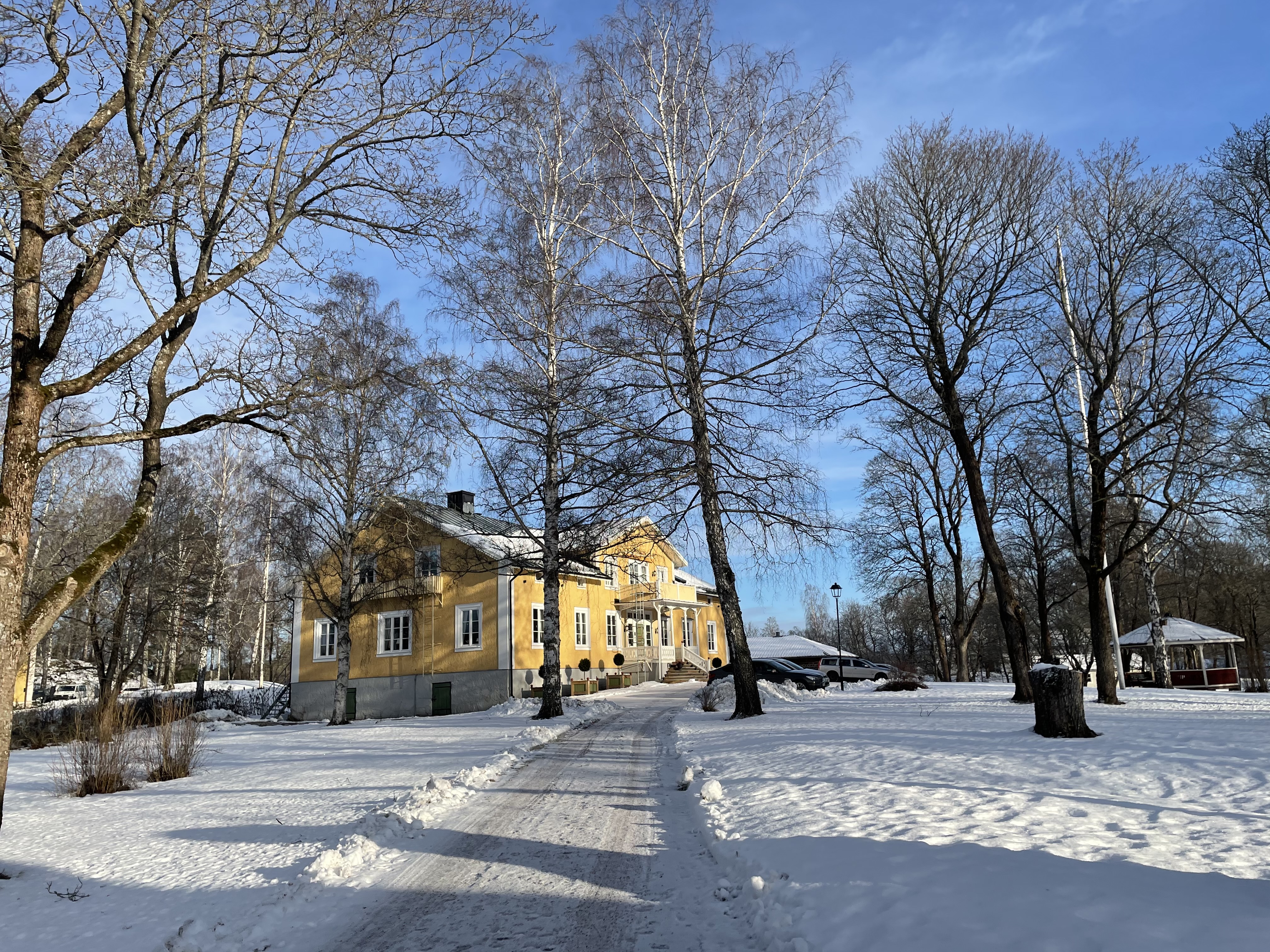 Gul herrgårdsbyggnad i vintermiljö.
