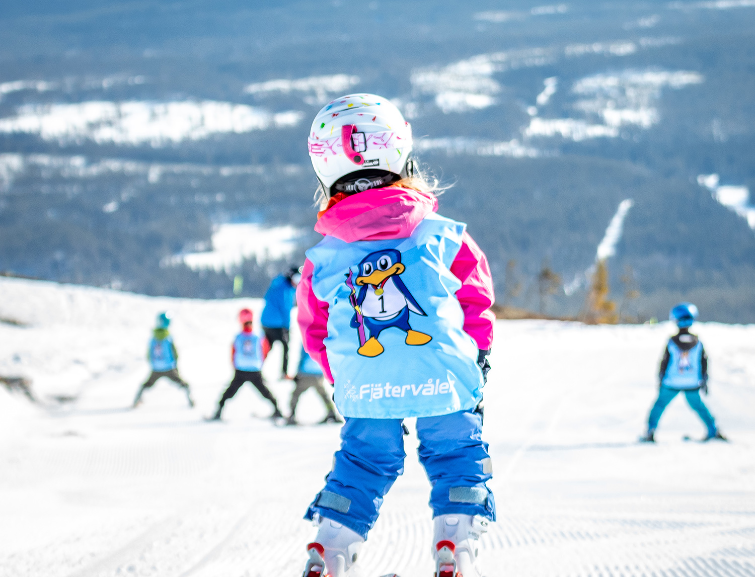Ett barn i väst åker skidor under en skidlektion.