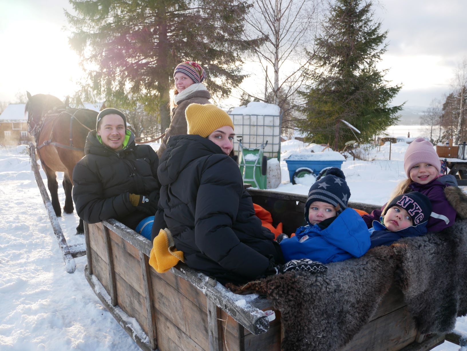 Familj sitter i släde med förspänd häst.