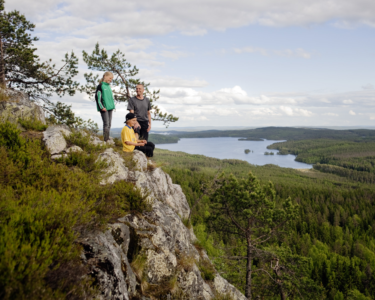 Tre personer står på ett berg och tittar på utsikten.