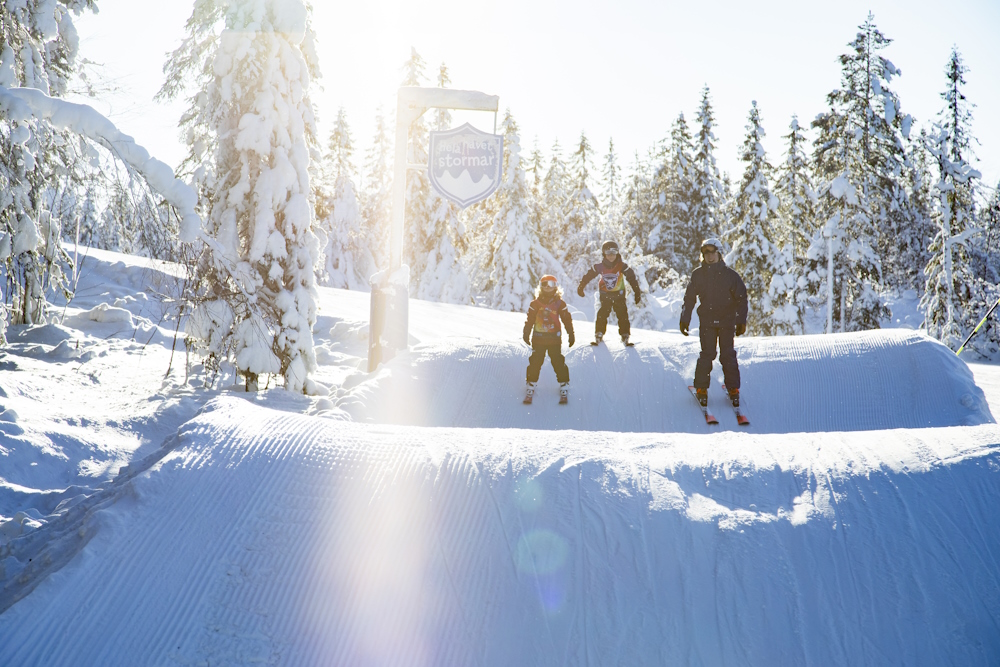 Två barn på skidskola som tar sig nerför backen.