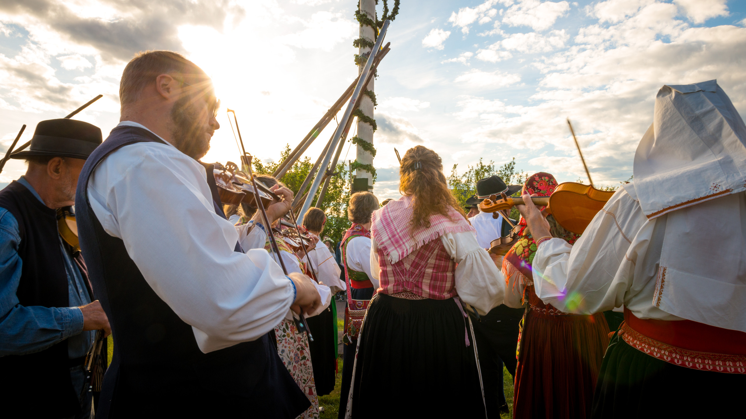 Musikanter som spelar runt midsommarstången.