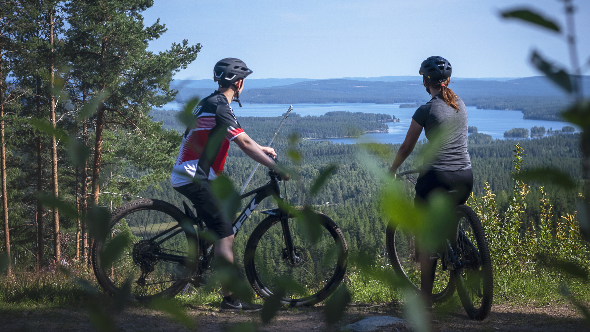 Two persons on mountainbike looking out at the view.