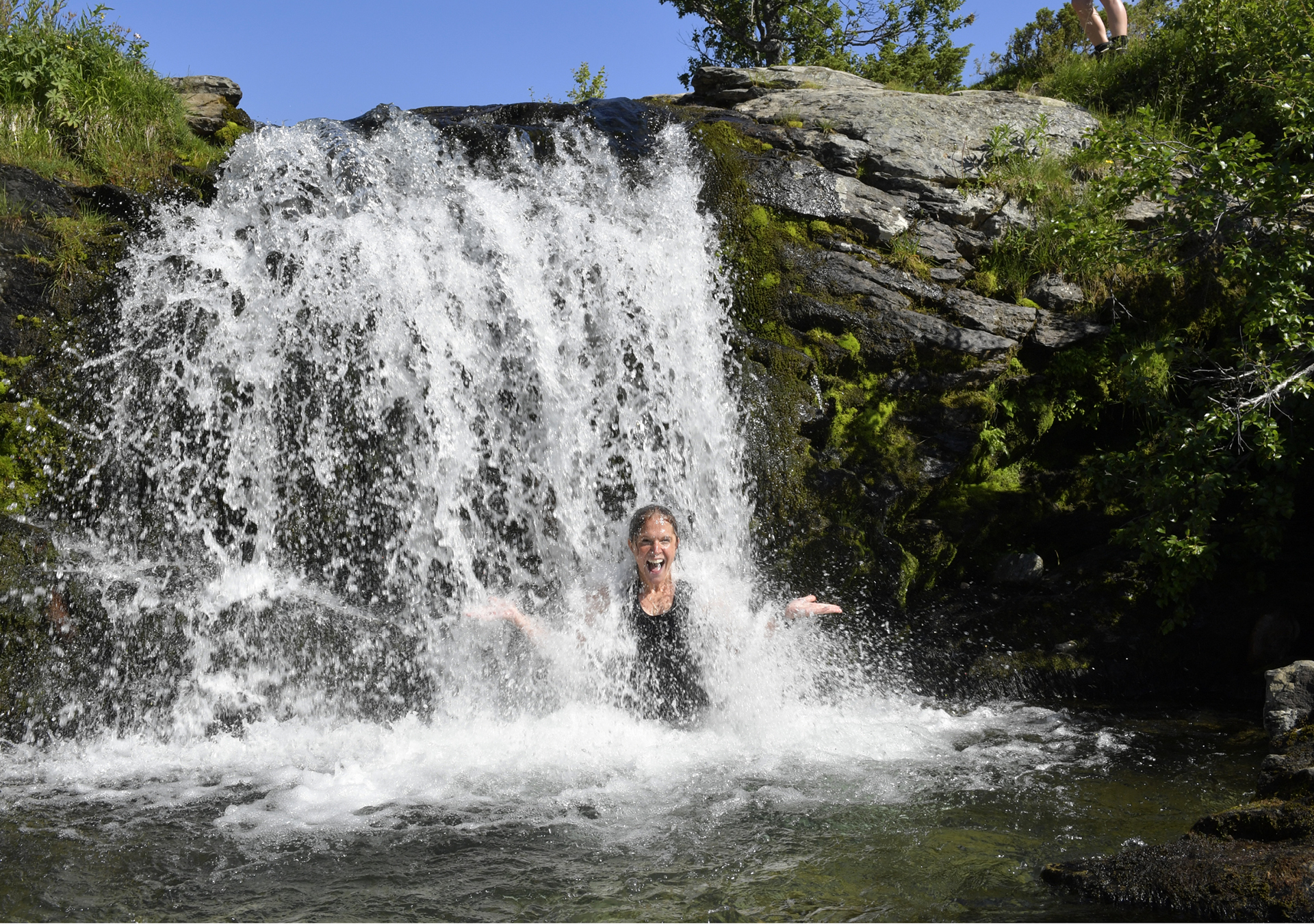Kvinna står mitt i vattenfallet.