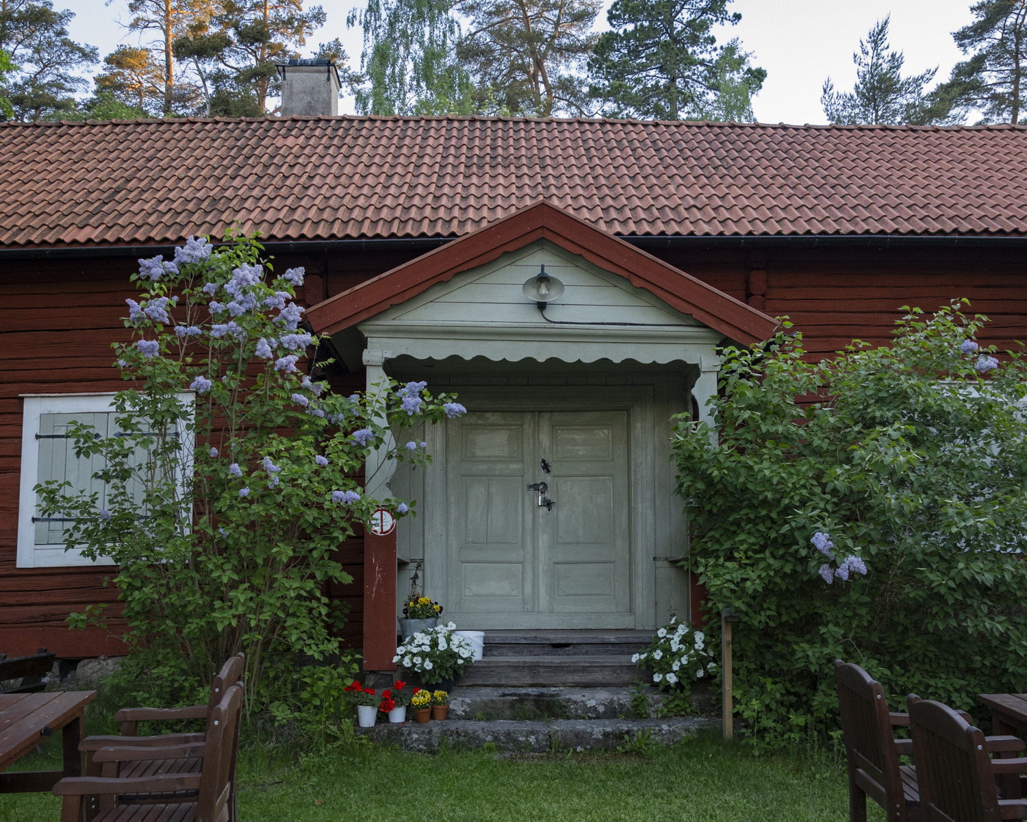 Ett falurött hus med grön dörr sommartid