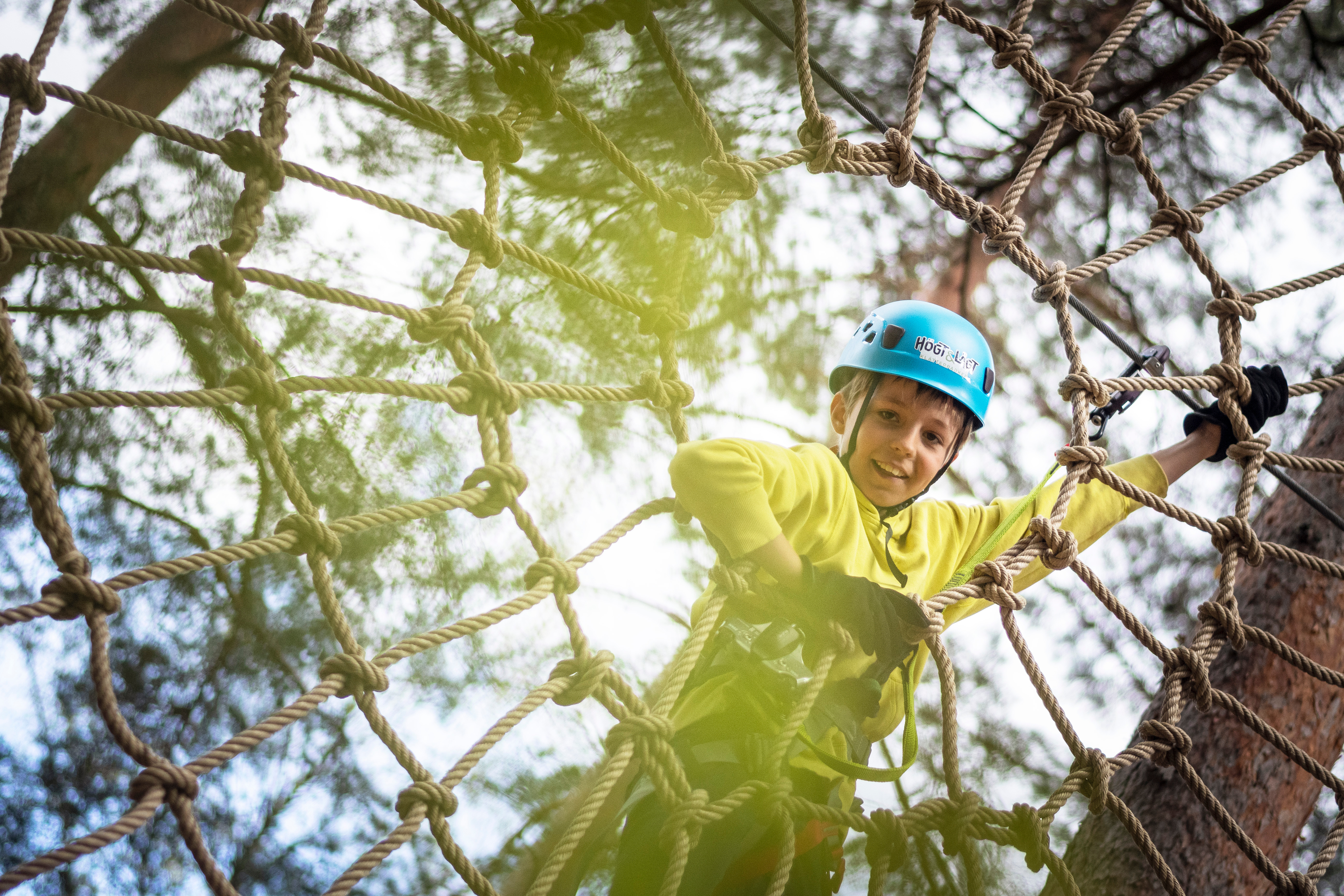Kille som klättar i en klätterpark.