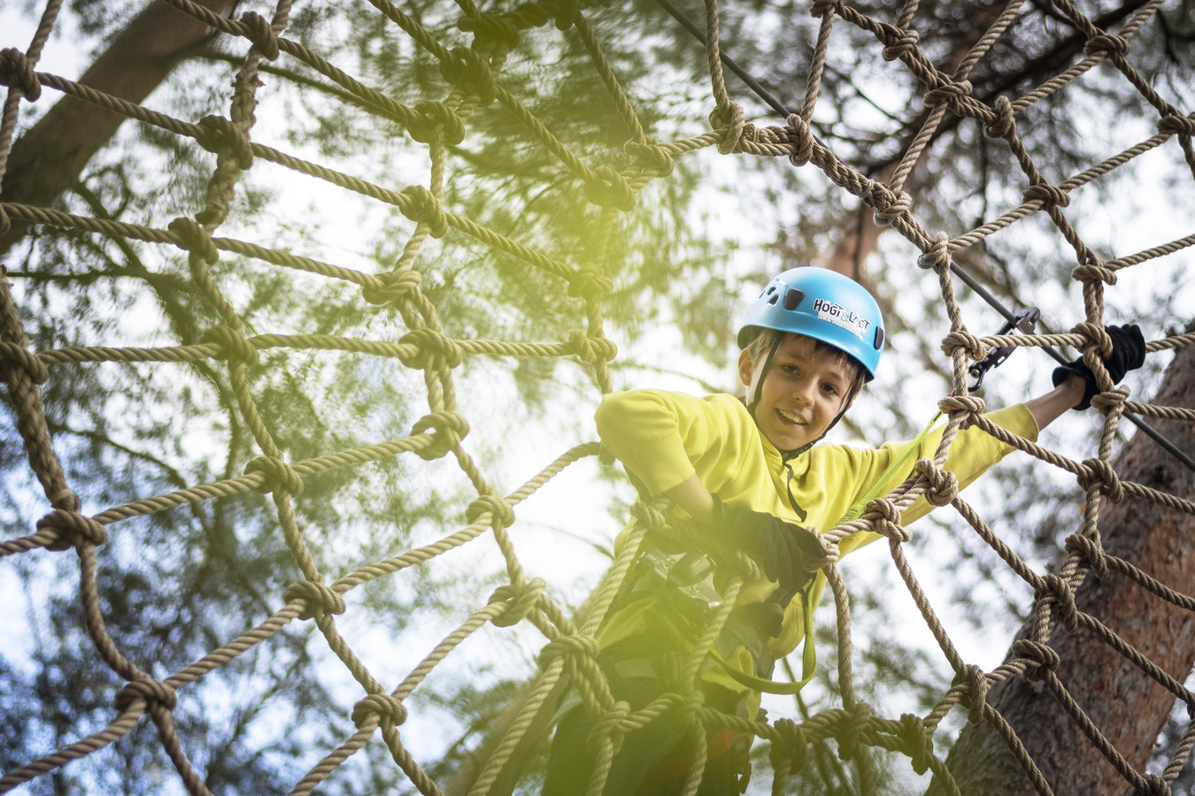 Kille som klättar bland träden.