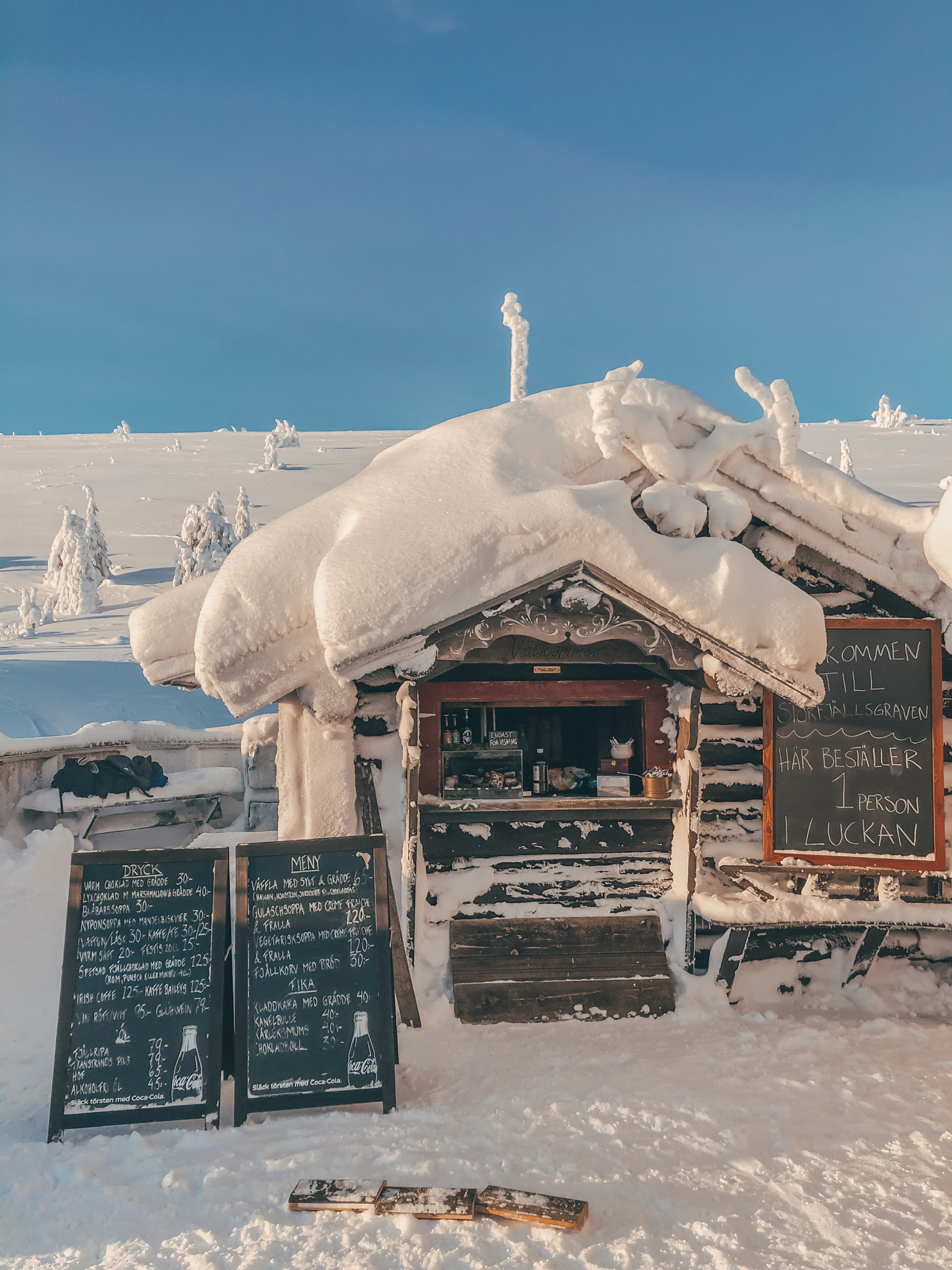En timmerstuga med tjockt med snö på taket, Storfjällsgravens café.