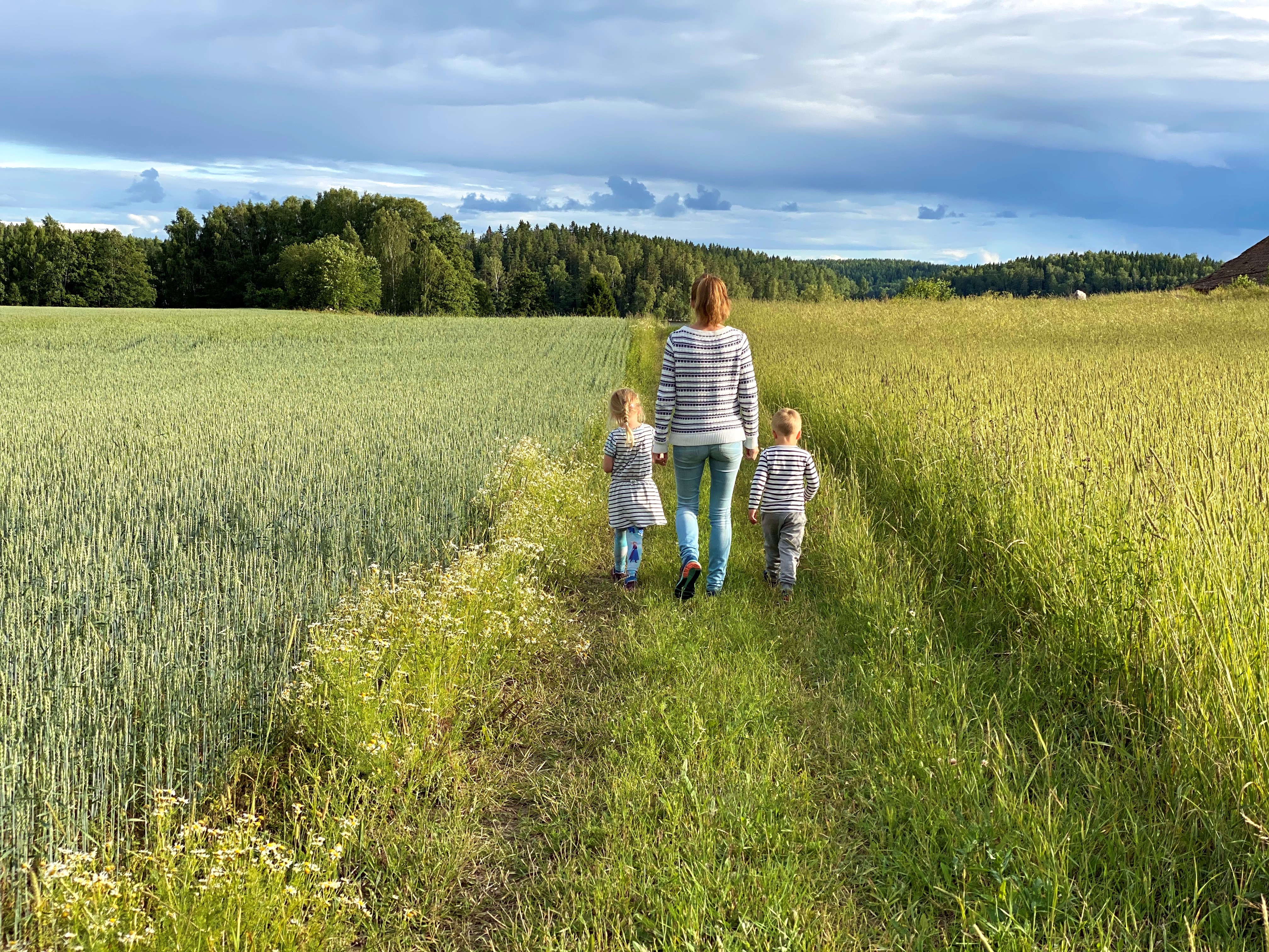 Mamma med barn går på stig vid en åker i Knutsbo.