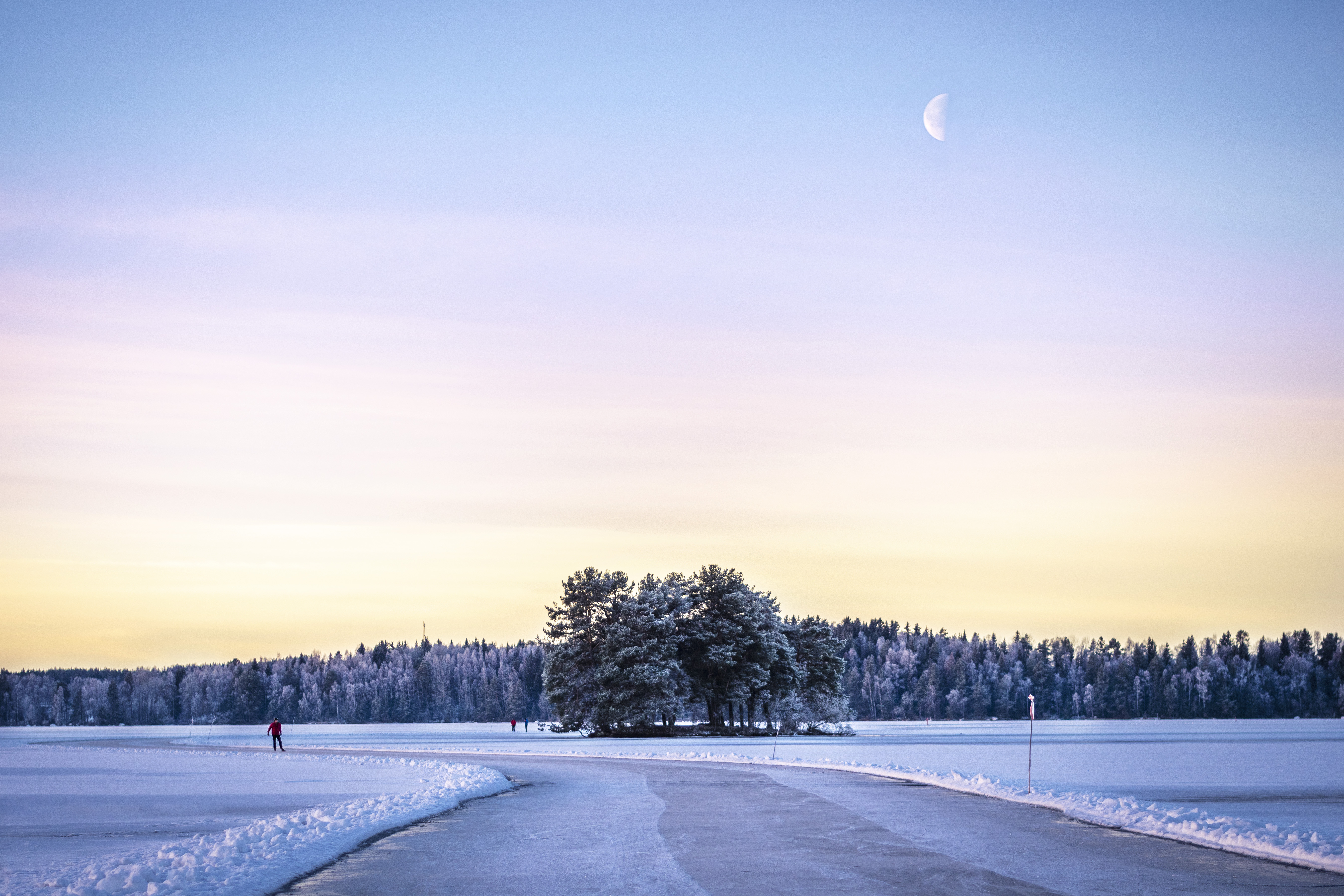 Vy över plogad isbana för skridskoåkning i skymningen.