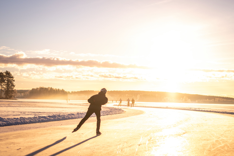 People ice skating in the sun.