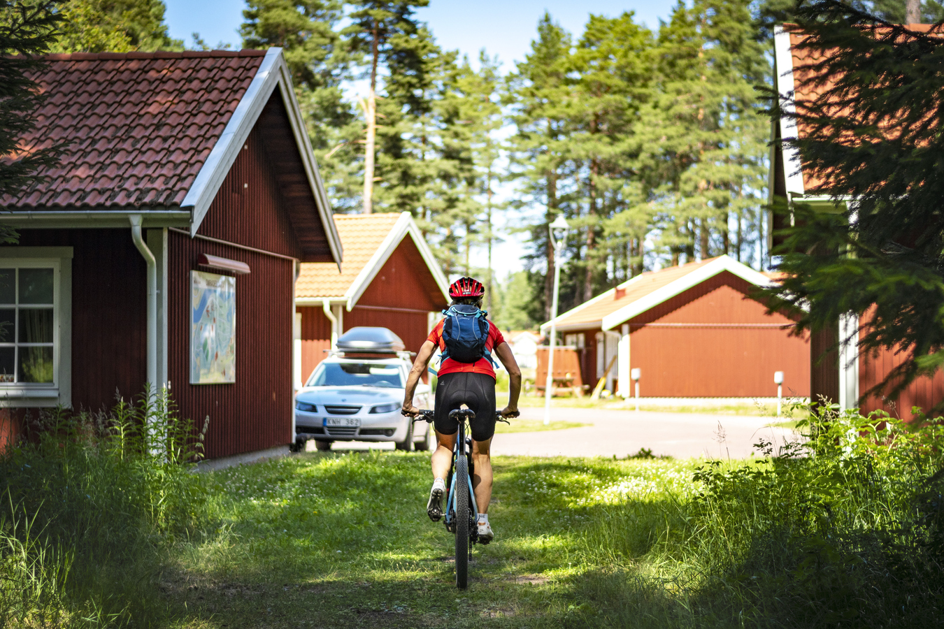Person cyklar bland stugor på Mora Parken camping.