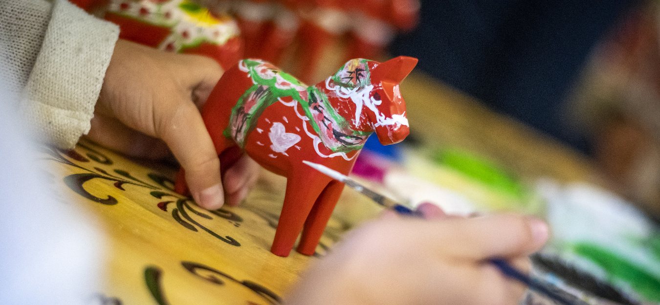 Barnhand målar egen dalahäst.