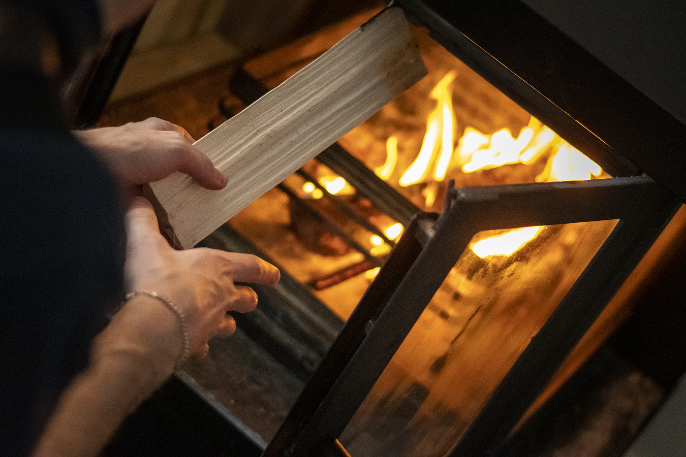 Lägger in vedträ i öppen eld.