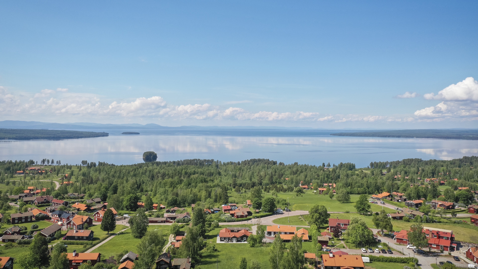 Utsikt över Tällberg med rödmålade stugor och Siljan som bakgrund.