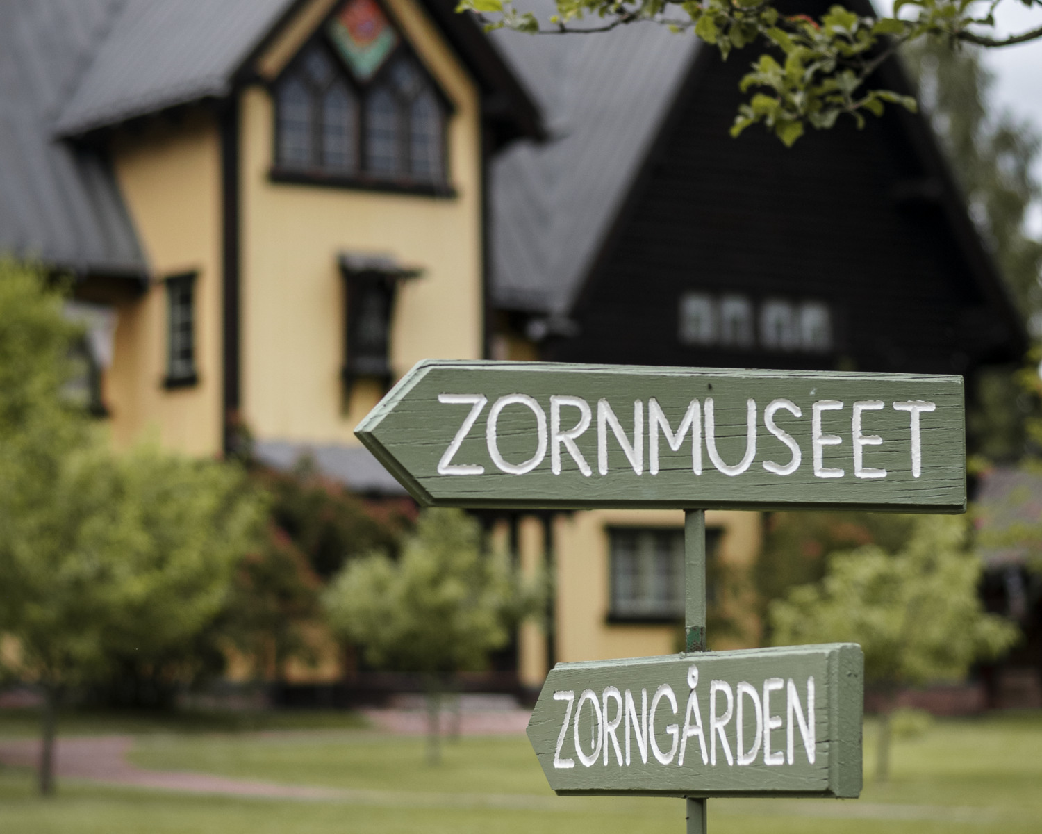 En skylt framför ett hus sommartid.