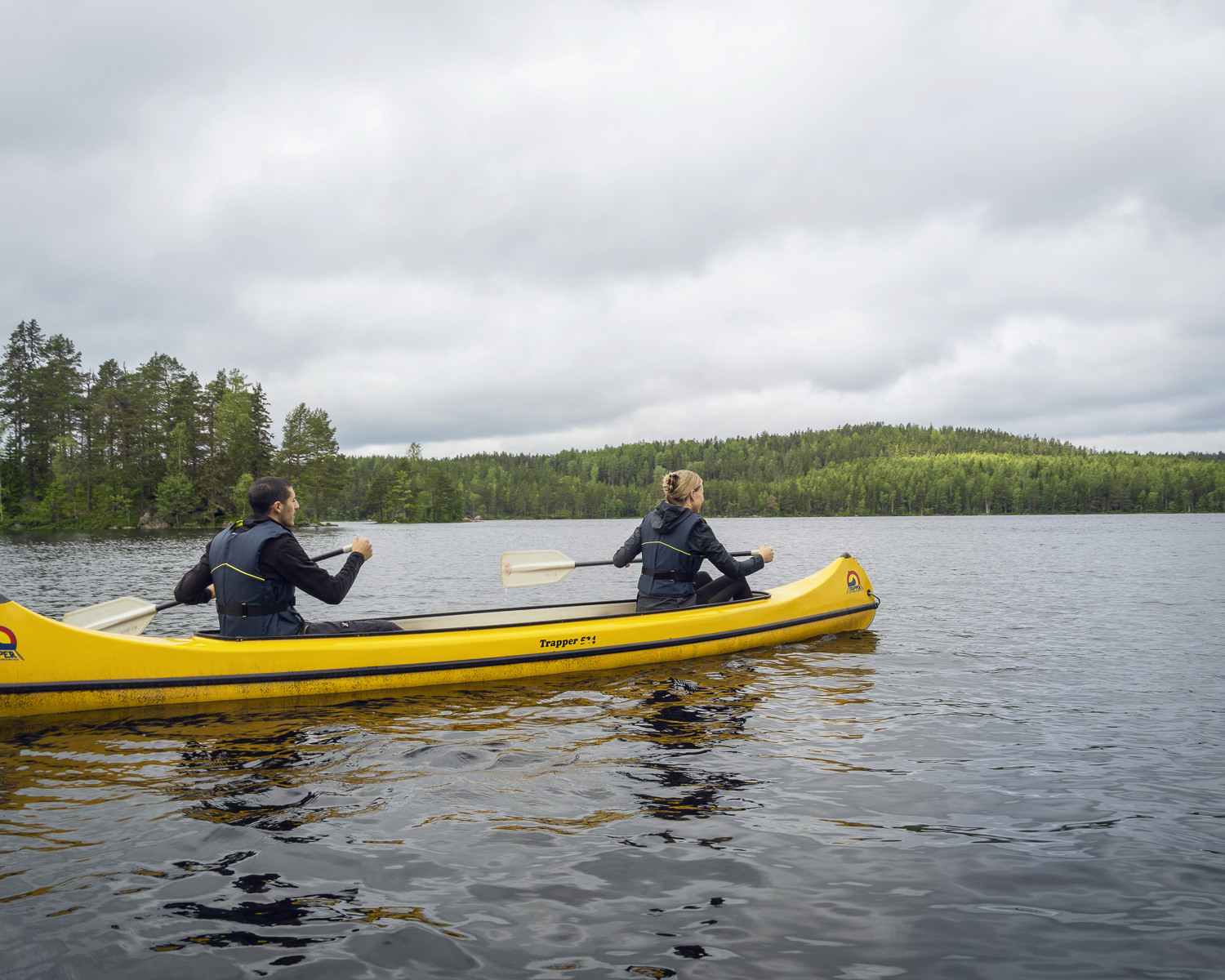 Två personer paddlar en gul kanot sommartid.