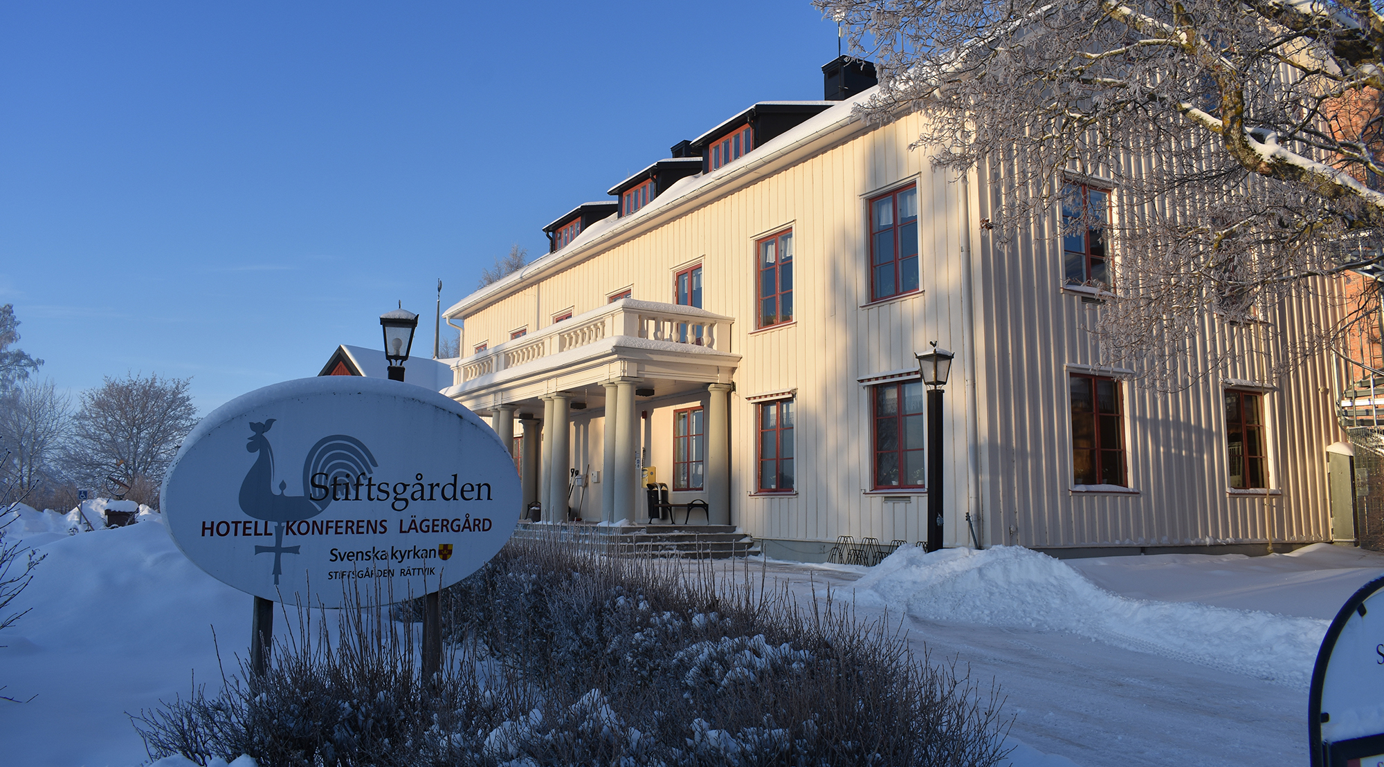 Ett stort vitt hus med skylten "Stiftsgården" framför.