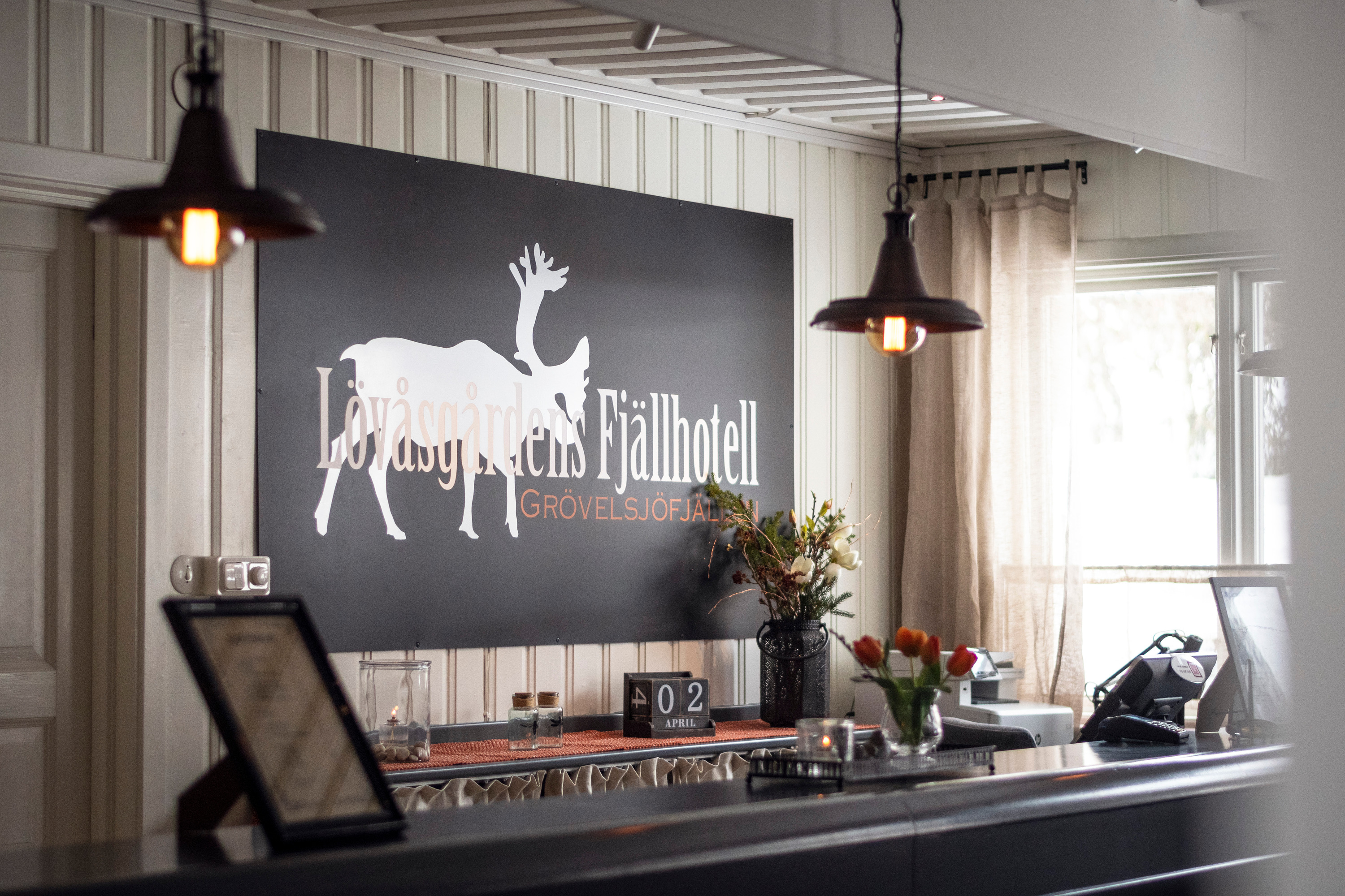 En hotellreception med en skylt där det står Lövåsgårdens fjällhotell.