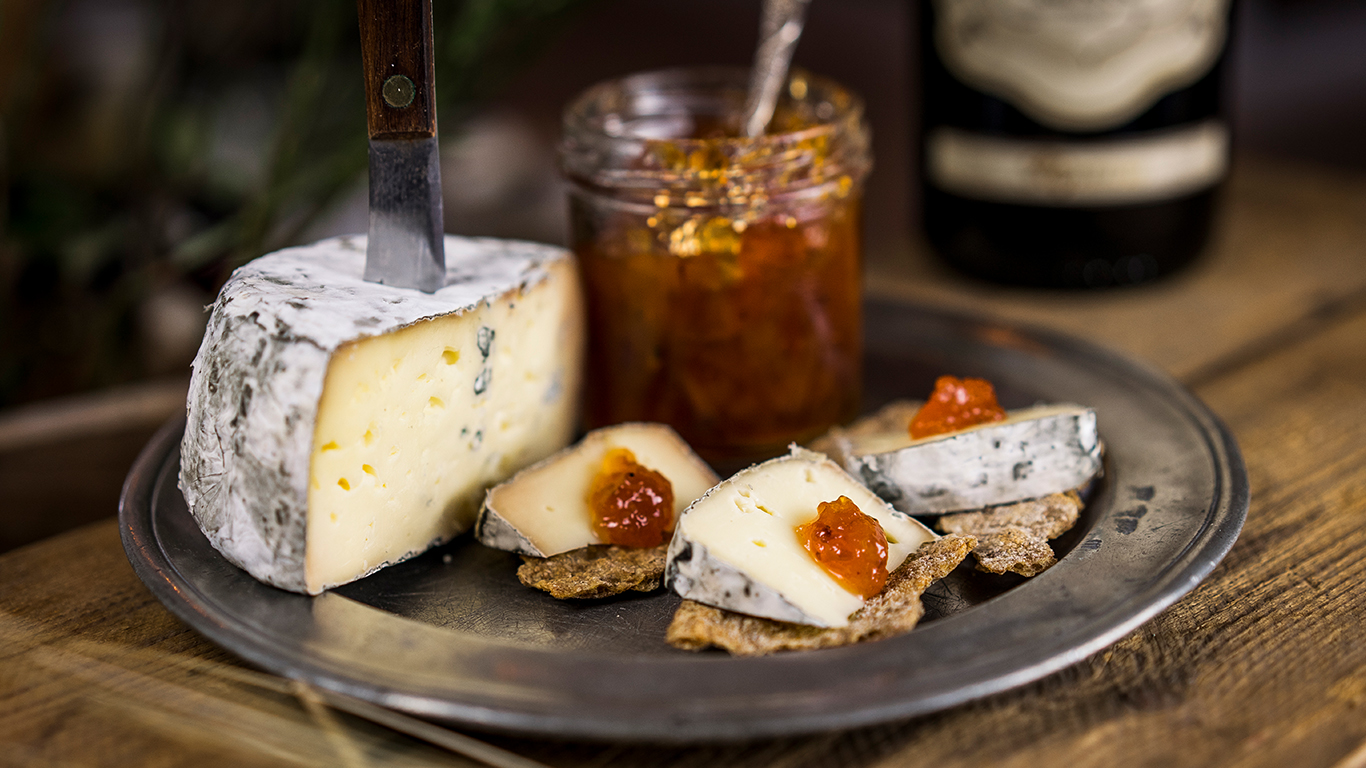 En ostbricka med marmelad, ost och knäckebrödsbitar.