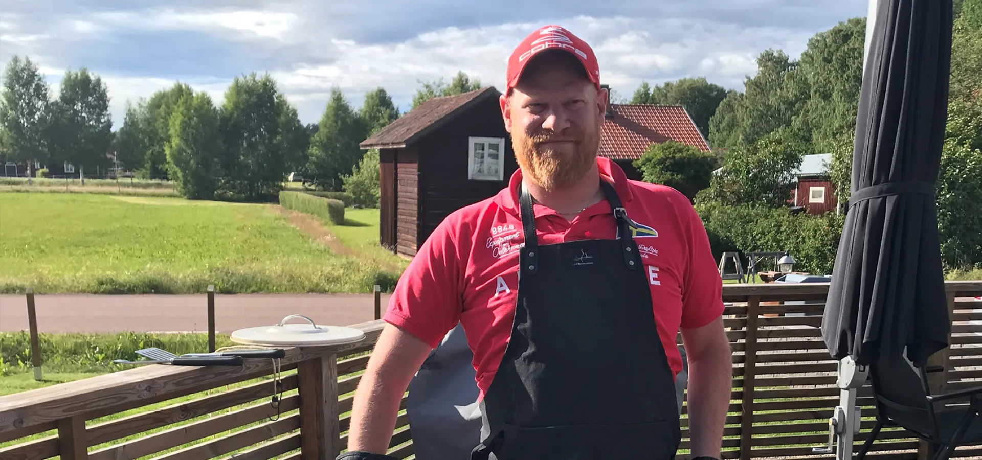 En man i förkläde står vid en grill.