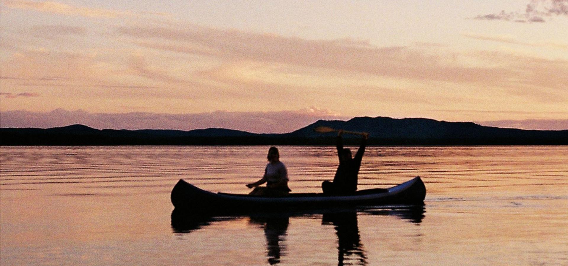 Två personer paddlar kanot i solnedgången på Siljan.