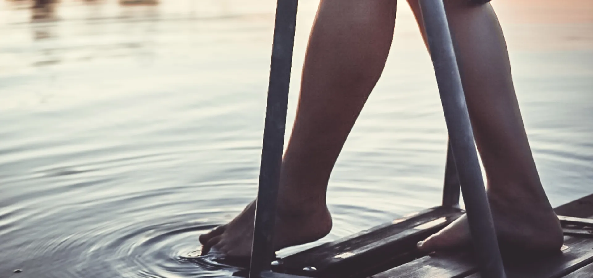 Doppar tårna i sjön från en brygga.