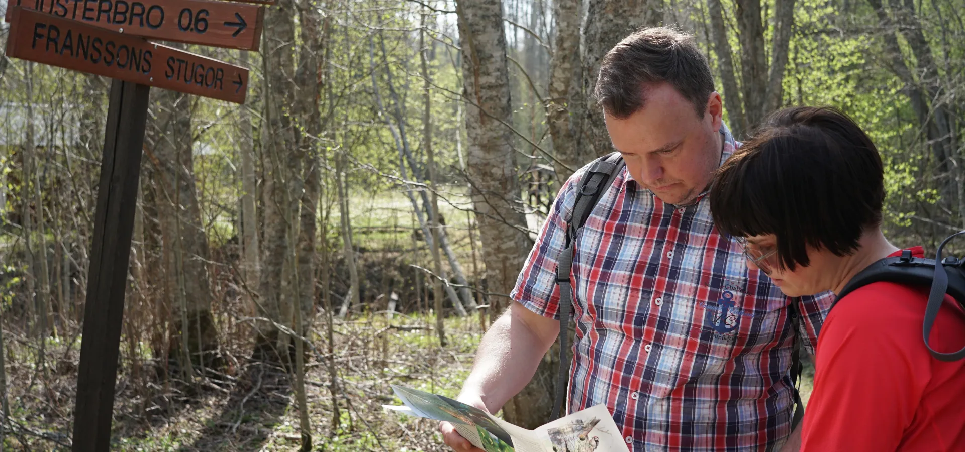 Två personer tittar på en karta i skogsmiljö.