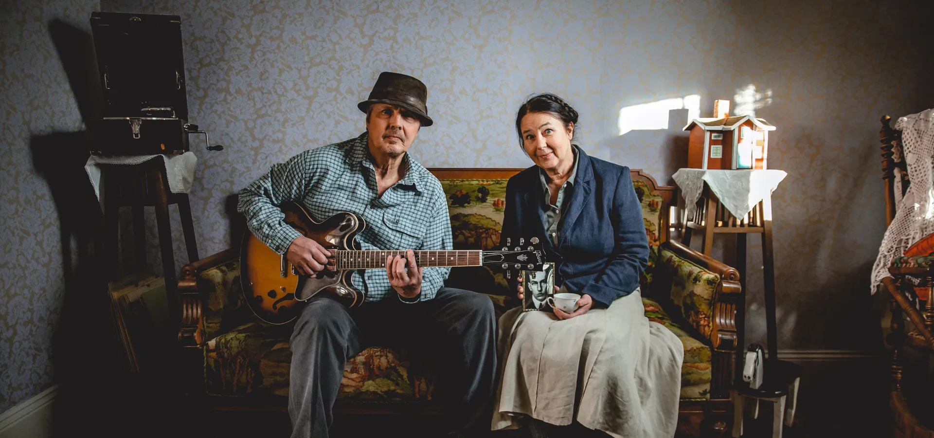 Par som spelar gitarr i en soffa.