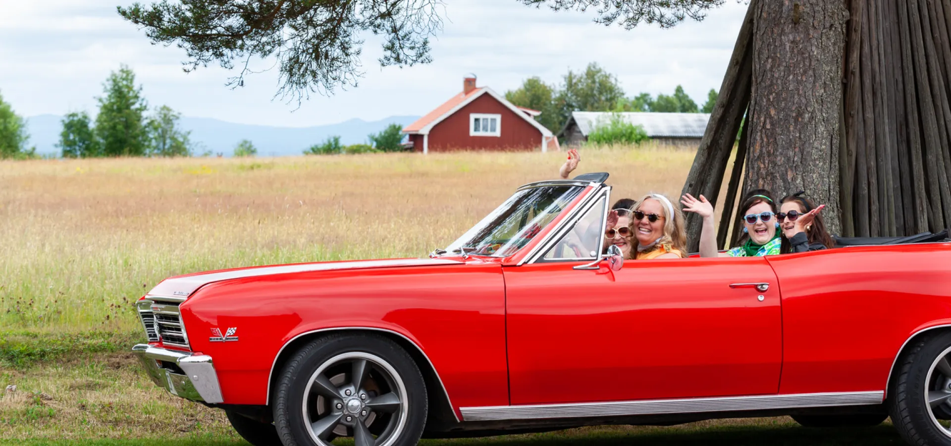 Kvinnor sitter i en äldre bil sommartid.