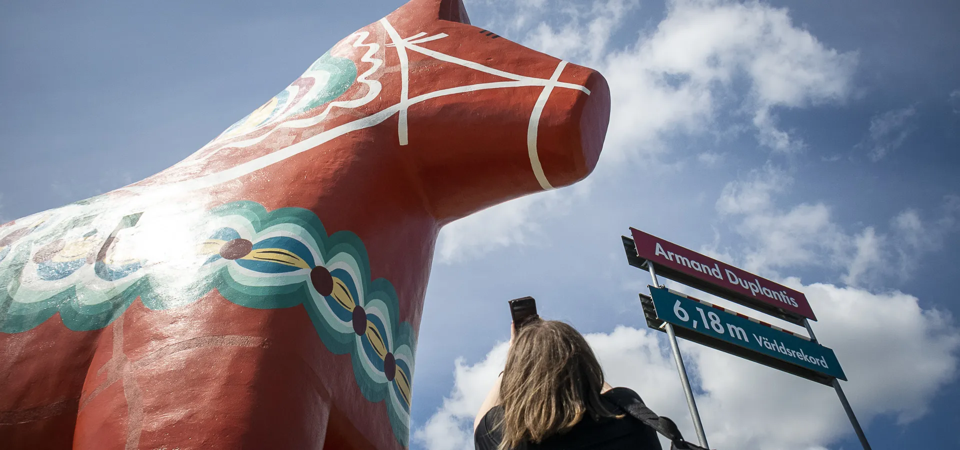 En kvinna fotar en gigantisk dalahäst.