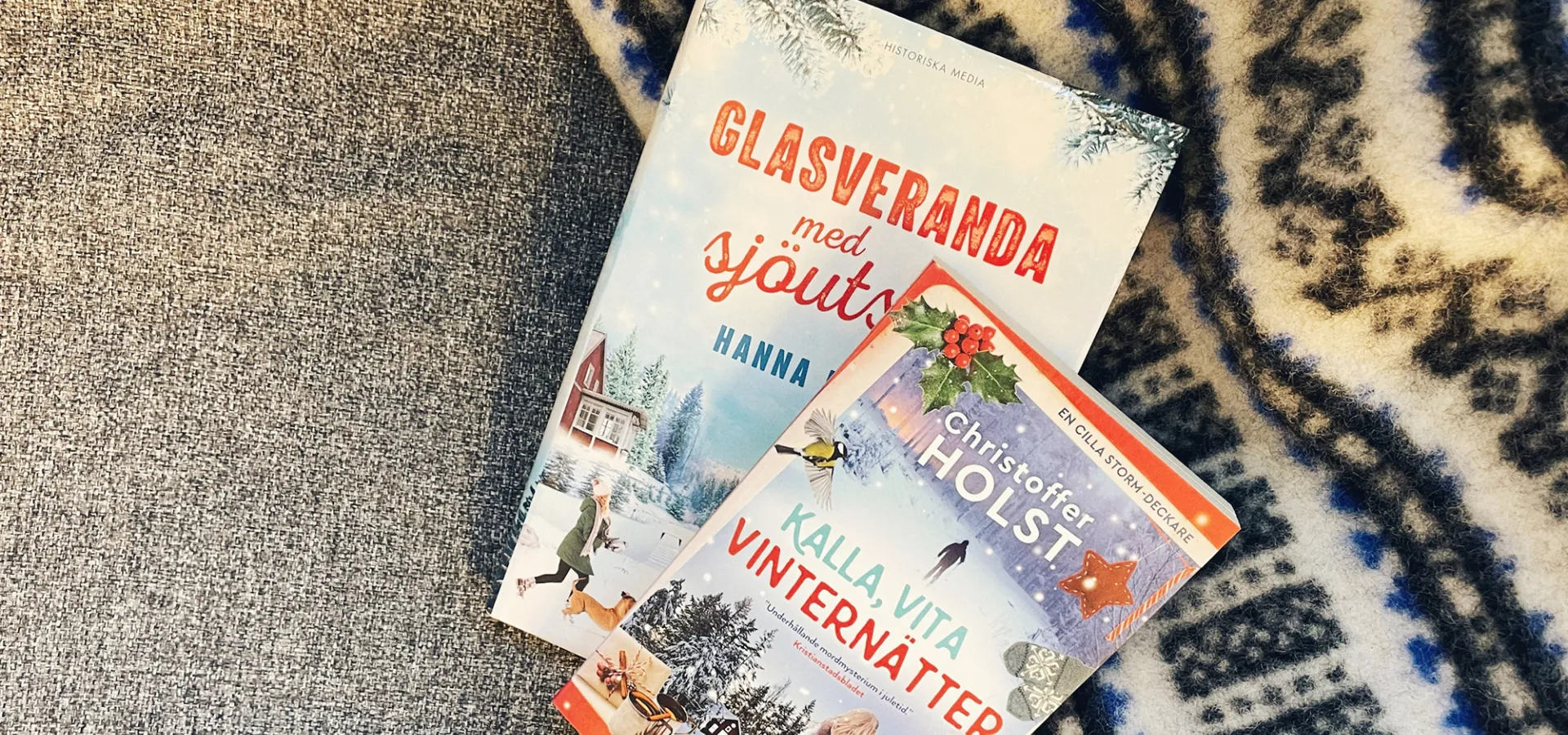 Två pocketböcker ligger på en svart och vit filt.