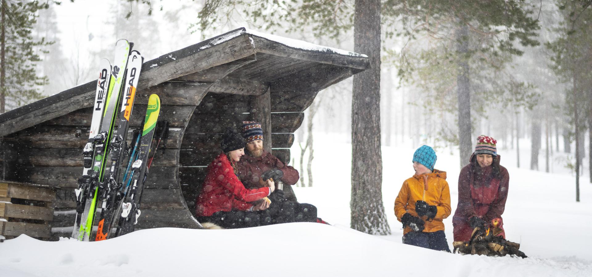 Familj som myser vid en slogbod i snön.