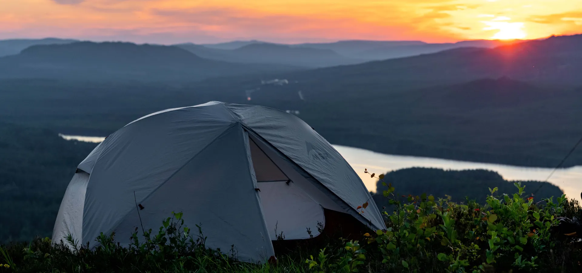 Tält framför vy över blånande berg.