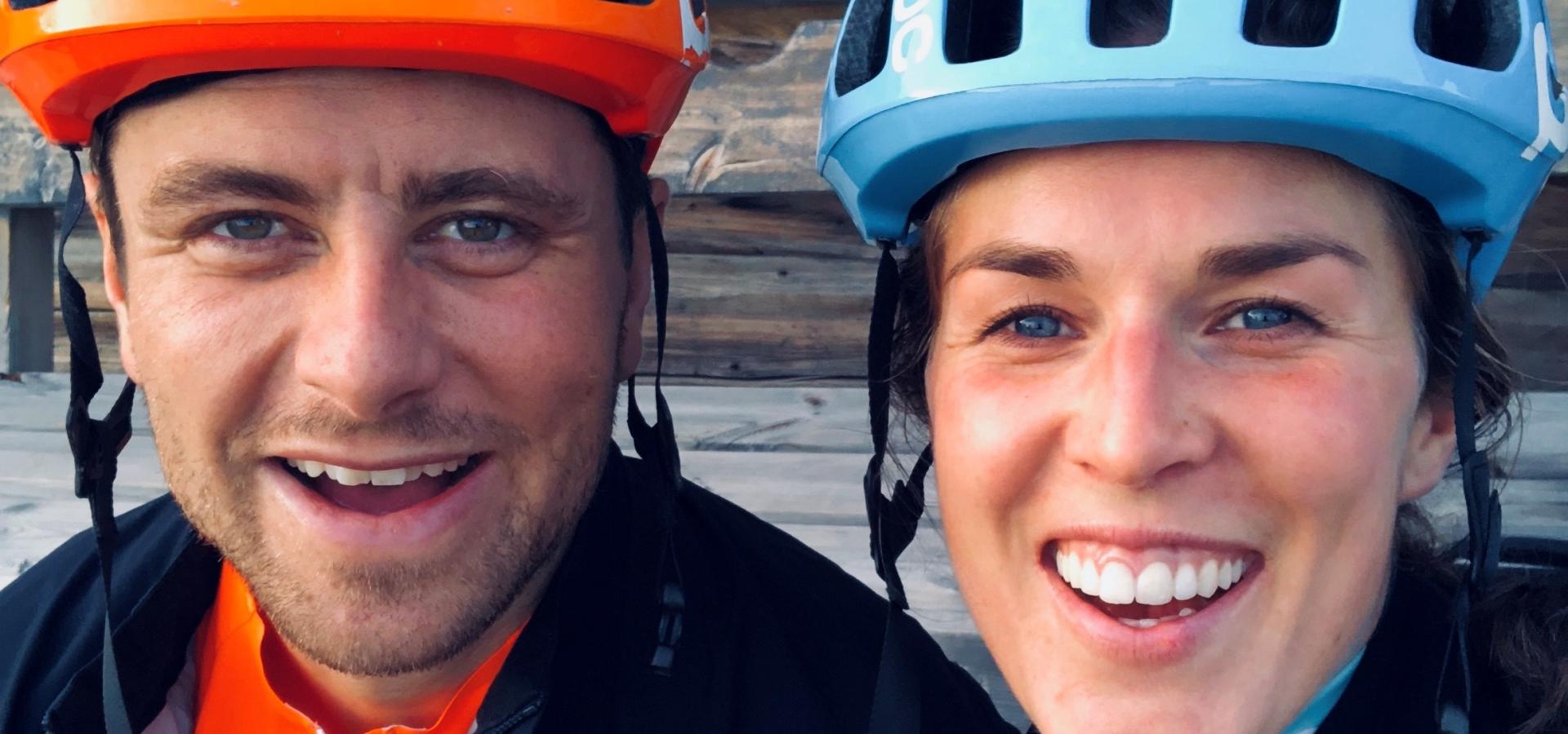 En kvinna och en man iförda cykelhjälmar ler mot kameran.