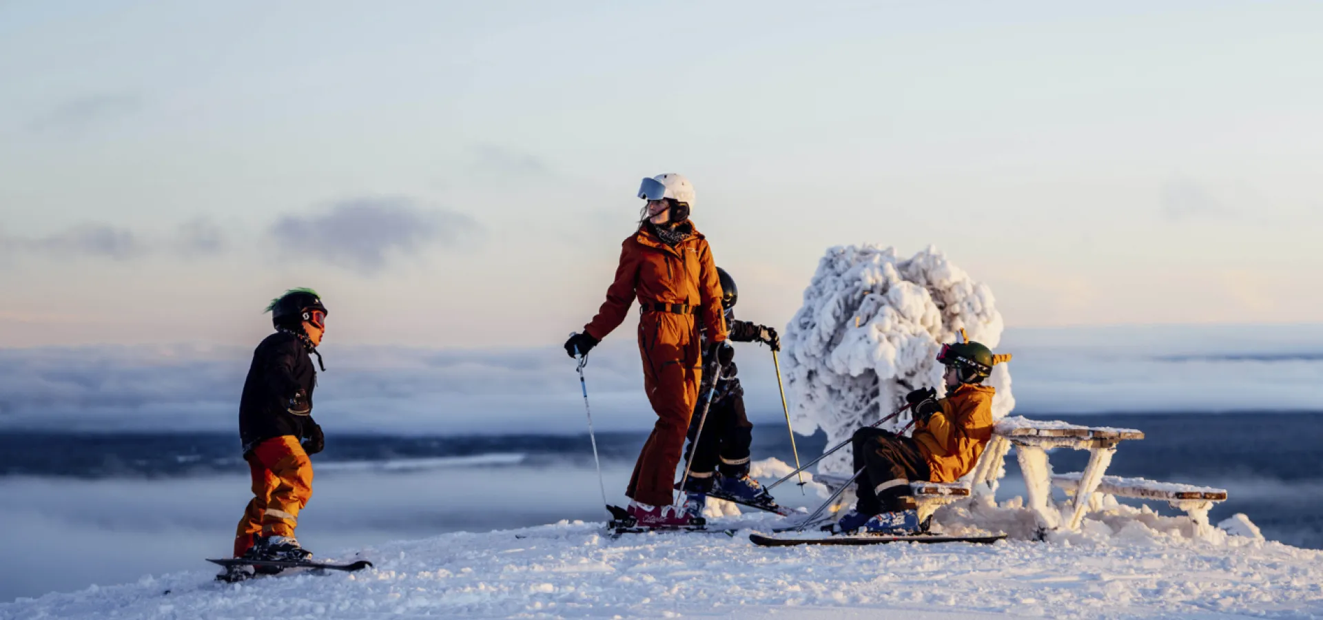 Family on top at the skislope with a clear sky behind them.