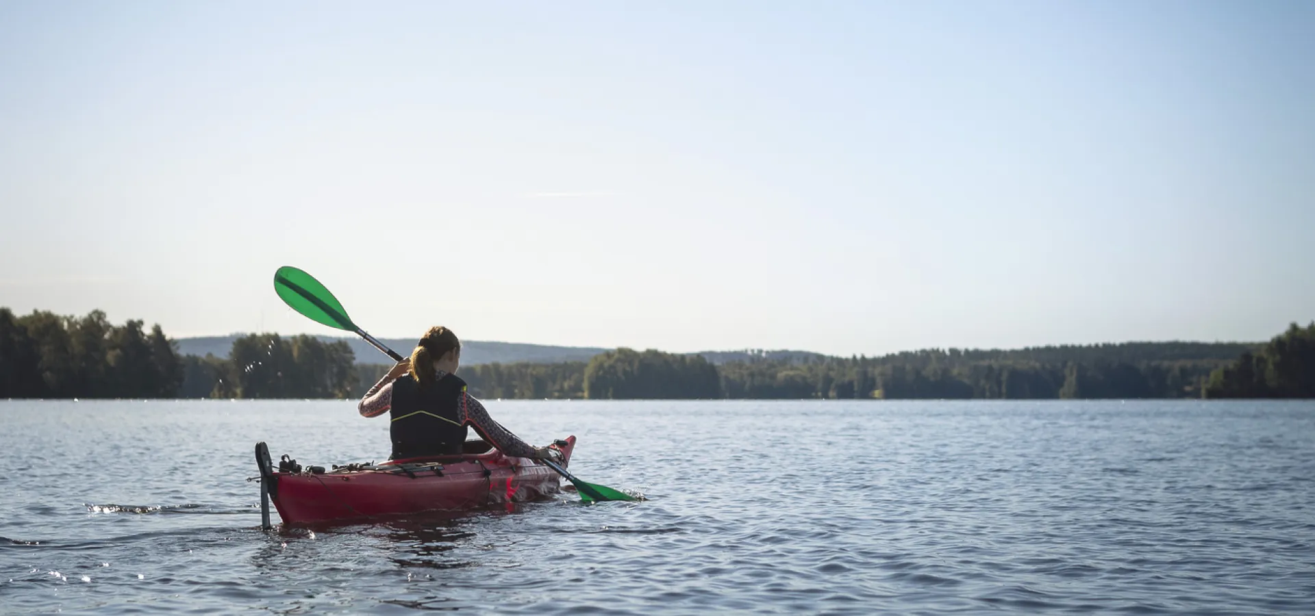 Kvinna som paddlar kajak på sjö.