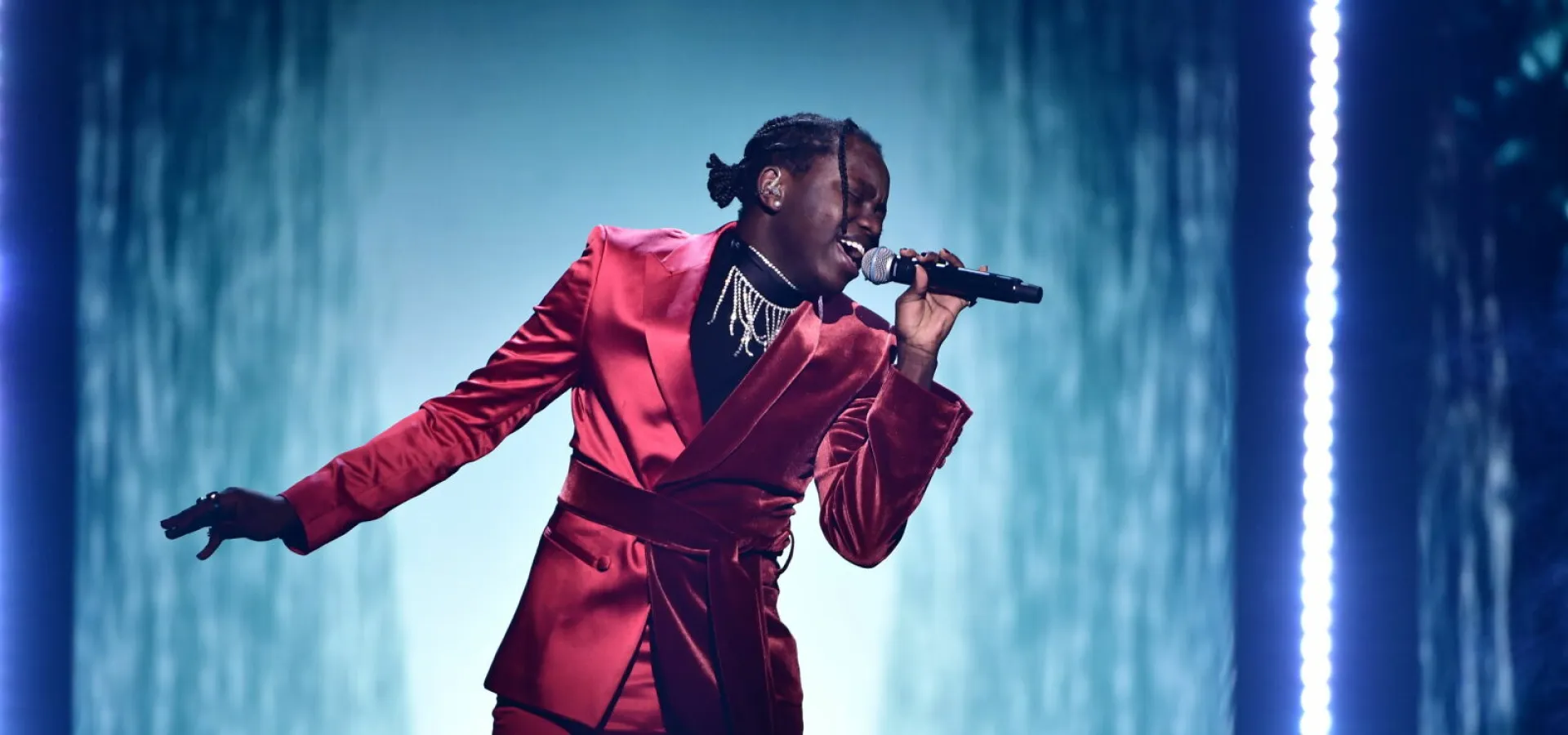 Tusse står på scen i röd kostym och sjunger.