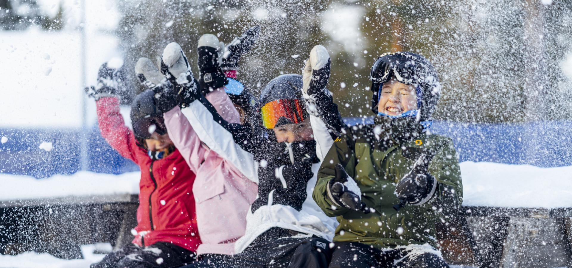 Glada barn kastar snö i luften.